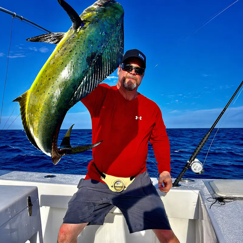 Man in red shirt holding a bright yellow-green mahi catch on Tamarindo boat