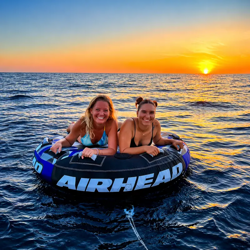 Two women tubing during a beautiful sunset boat tour in Tamarindo