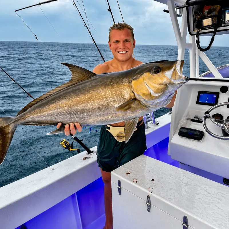 Man holding beautiful golden fish in the cockpit of Captain Willy boat